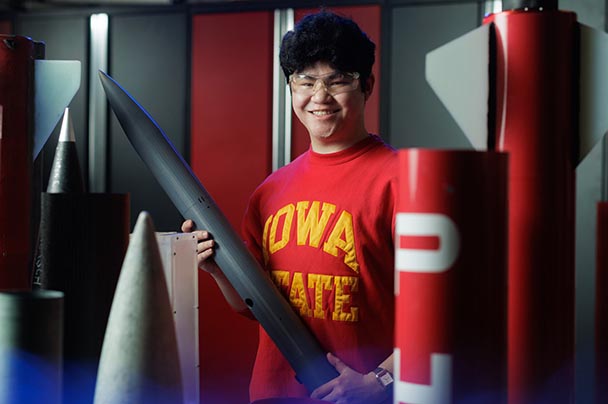 A student poses with rockets.