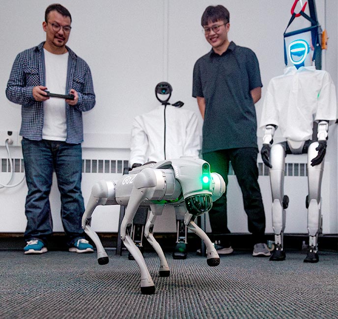 Two researchers work on commands for a dog-like robot.
