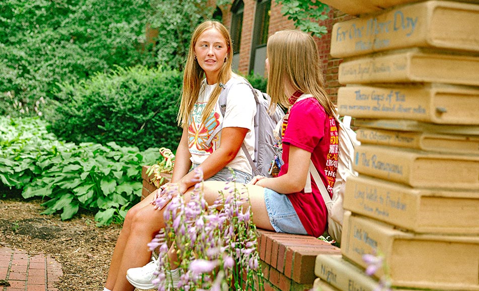 Two students sit near a sculpture in the Lagomarcino courtyard.