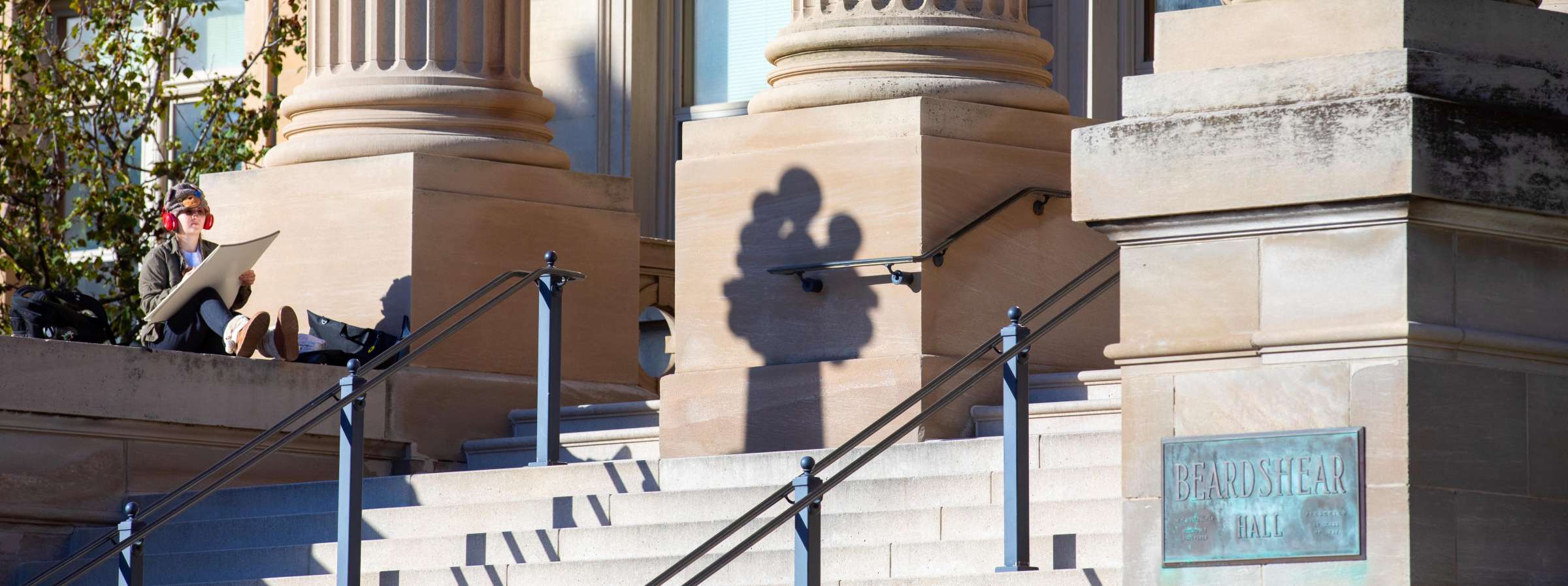 A student draws on the steps of Beardshear Hall